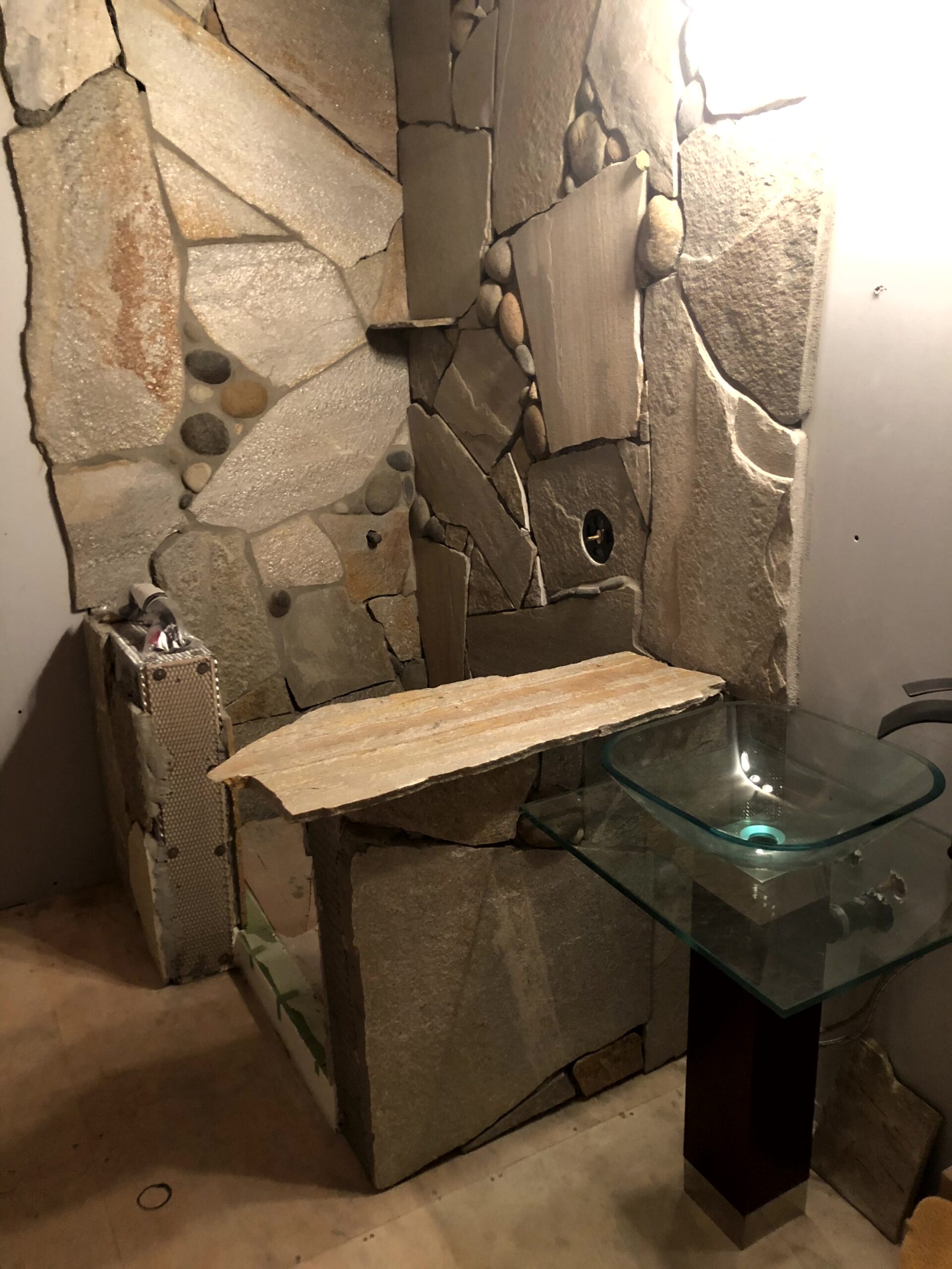 Waterman-Construction-Custom Waterman Construction custom home bathroom remodel with rock backsplash in a shower with glass sink.